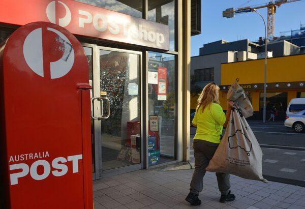 A worker carries a sack of letters after emptying a post box outside an Australia Post office in Sydney on June 26, 2015. (Peter Parks/AFP via Getty Images)