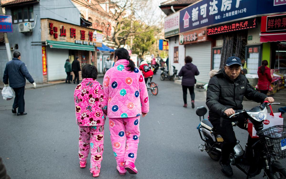 A woman and a girl in pink pajamas walk down a street in Shanghai on Jan. 31, 2017. (JOHANNES EISELE/AFP via Getty Images)