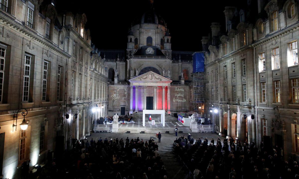 French President Emmanuel Macron pays his respects in front of the coffin of slain teacher Samuel Paty in the courtyard of the Sorbonne university during a national memorial event, in Paris, France, on Oct. 21, 2020. (Francois Mori/Pool via Reuters)