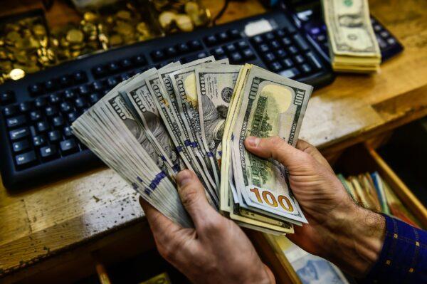 A man holds up U.S. cash in this file photo. (Yasin Akgul/AFP via Getty Images)
