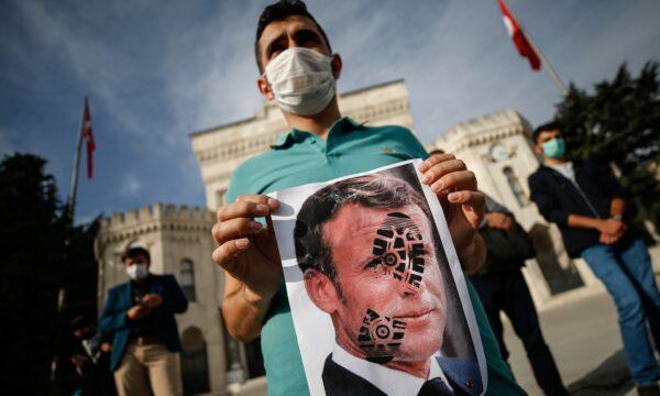 A youth holds a photograph of France's President Emmanuel Macron, stamped with a shoe mark, during a protest against France in Istanbul, on Oct. 25, 2020. (Emrah Gurel/AP Photo)