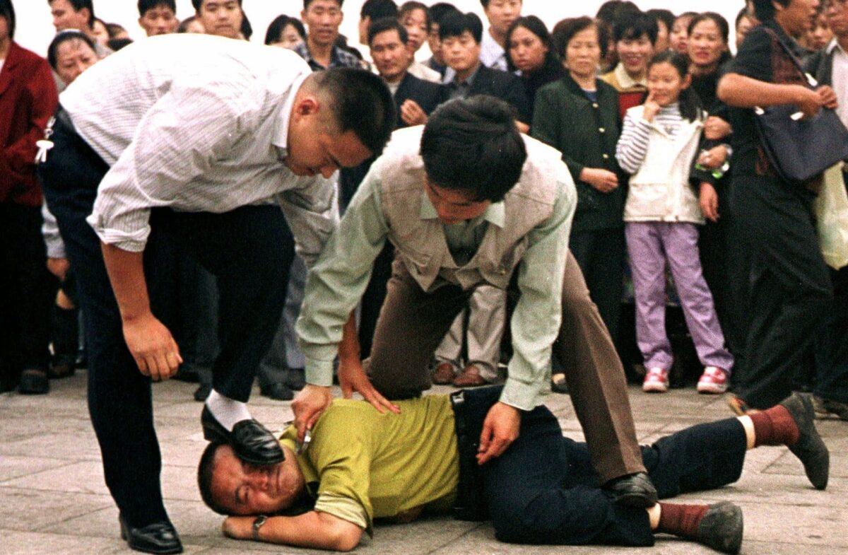 Police detain a Falun Gong protester in Tiananmen Square as a crowd watches in Beijing, China, in this Oct. 1, 2000 photo. (Chien-min Chung/AP Photo)