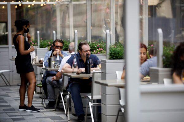 A waiter talks with patrons at a patio in Yorkville in Toronto on June 26, 2020. (The Canadian Press/Cole Burston)