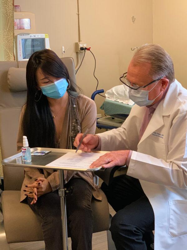 Chen Cao (L) prepares to take the first dose of a new COVID-19 vaccine trial administered by Dr. Philip Robinson at Hoag Memorial Hospital in Newport Beach, Calif., on Oct. 26, 2020. (Courtesy of Hoag Memorial Hospital)