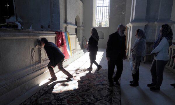 People kiss the cross on the altar in the Holy Savior Cathedral, damaged by shelling by Azerbaijan's artillery, during a military conflict in Shushi, the separatist region of Nagorno-Karabakh, on Oct. 24, 2020. (AP Photo)