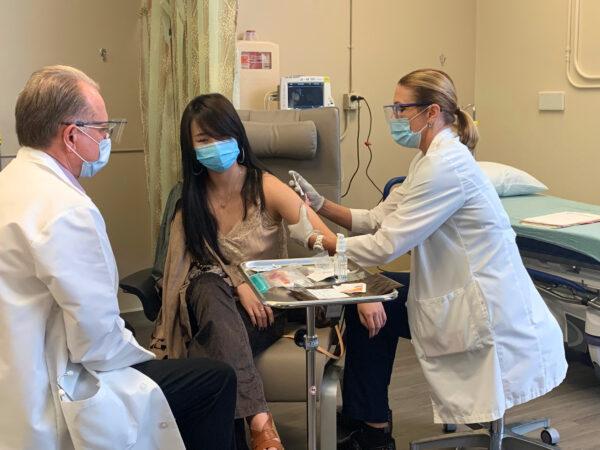 Chen Cao (C) receives the first dose of a trial COVID-19 vaccine as administrator Dr. Philip Robinson (L) observes at Hoag Memorial Hospital in Newport Beach, Calif., on Oct. 21, 2020. (Courtesy of Hoag Memorial Hospital)