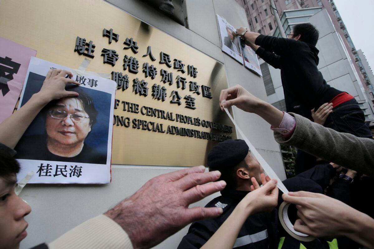 Protesters try to stick photos of missing booksellers, one of which shows Gui Minhai (L), during a protest outside of the Hong Kong Liaison Office on Jan. 3, 2016. (Vincent Yu/The Associated Press)