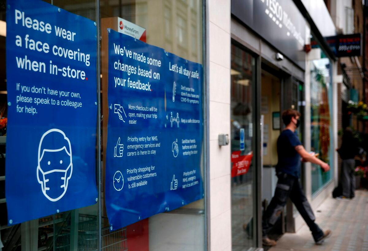 Signs in the window of a Tesco Metro supermarket ask customers to wear a face mask or covering due to the CCP virus pandemic, in London, on Sept. 23, 2020. (Hollie Adams/AFP via Getty Images)