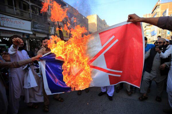 Pakistanis burn a French national flag during a protest following French President Emmanuel Macron's comments over the Muhammad caricatures, in Peshawar on Oct. 26, 2020. (Abdul Majeed/AFP via Getty Images)