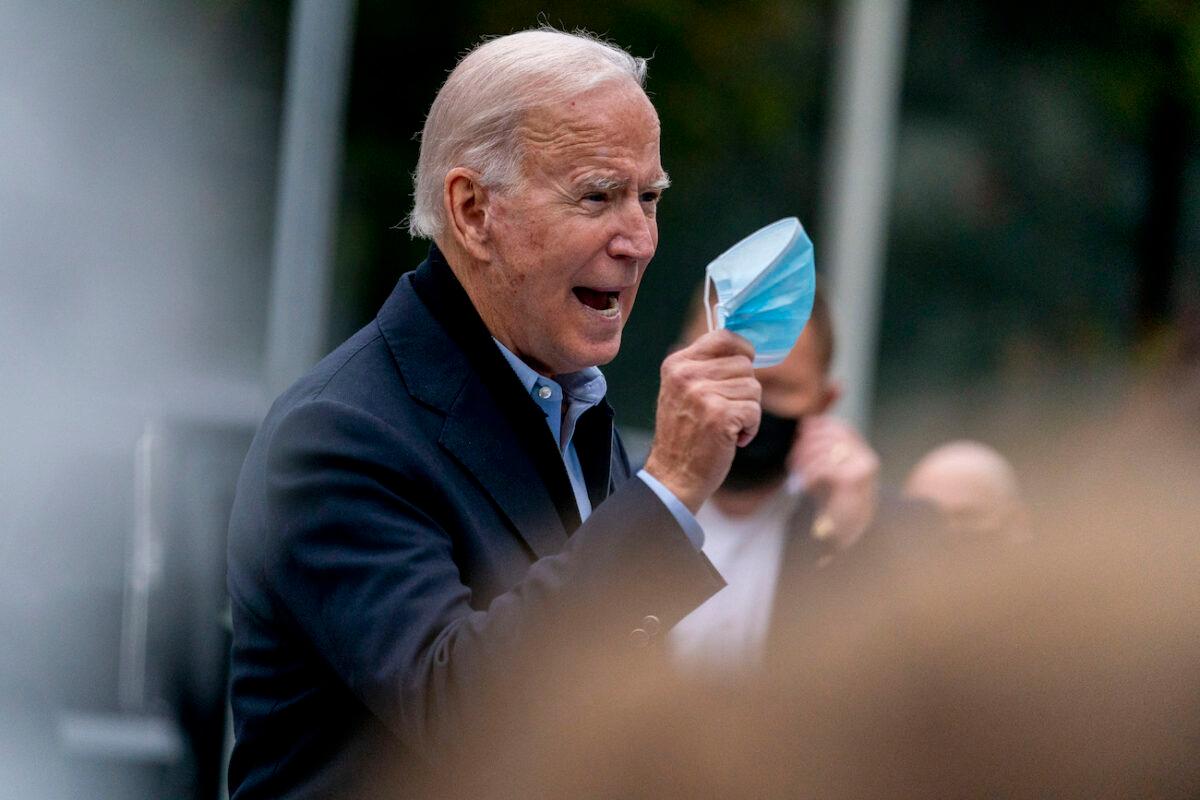 Democratic presidential candidate Joe Biden holds up his mask as he speaks to members of the media outside a voter service center, in Chester, Pa., on Oct. 26, 2020. (Andrew Harnik/AP Photo)
