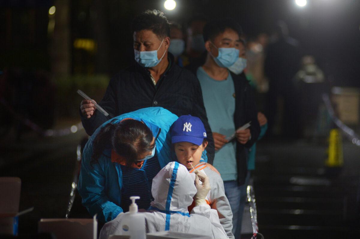 A medical worker in a protective suit collects a swab from a child for nucleic acid testing, following new cases of coronavirus disease (COVID-19) in Qingdao, Shandong province, China, on Oct. 13, 2020. (CNS Photo via Reuters)