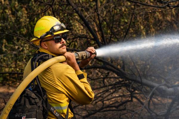 A firefighter sprays water to contain the Blue Ridge Fire in Yorba Linda, Calif., on Oct. 27, 2020. (John Fredricks/The Epoch Times)