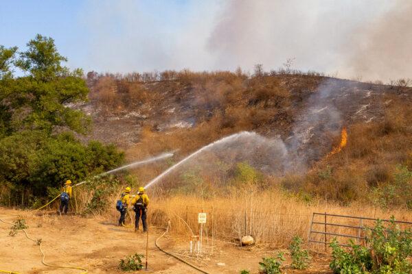 Firefighters spray water on the Blue Ridge Fire in Yorba Linda, Calif., on Oct. 27, 2020. (John Fredricks/The Epoch Times)