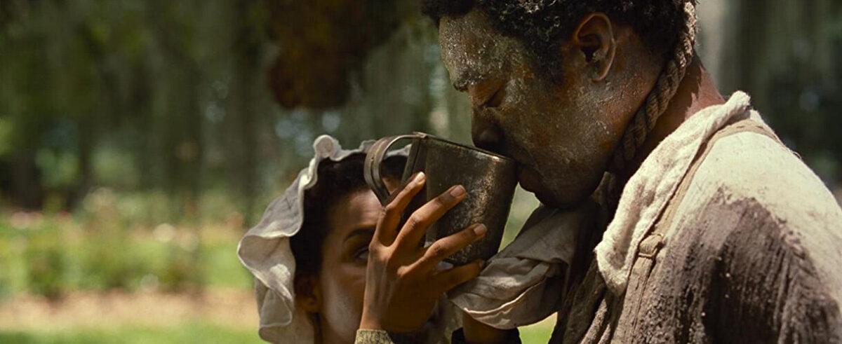 Solomon Northrup (Chiwetel Ejiofor), enduring a semi-lynching is given water by a house slave in "12 Years a Slave." (Twentieth Century Fox)