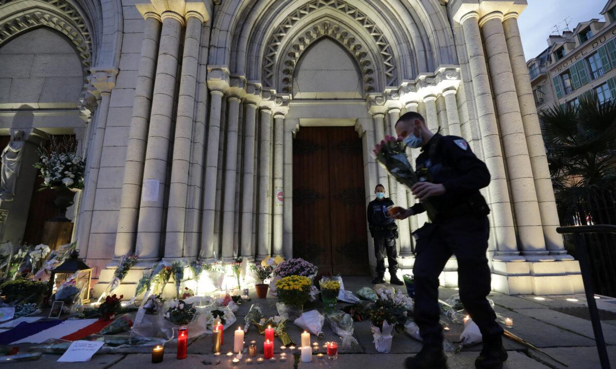 A policeman carries flowers in front of the Notre Dame church in tribute to the victims of a deadly knife attack in Nice, France, on Oct. 30, 2020. (Eric Gaillard/Reuters)