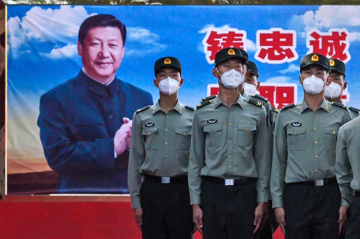 Soldiers of the People's Liberation Army's Honor Guard Battalion wear protective masks as they stand at attention in front of a photo of Chinese Communist Party leader Xi Jinping at their barracks outside the Forbidden City, near Tiananmen Square, in Beijing, on May 20, 2020. (Kevin Frayer/Getty Images)