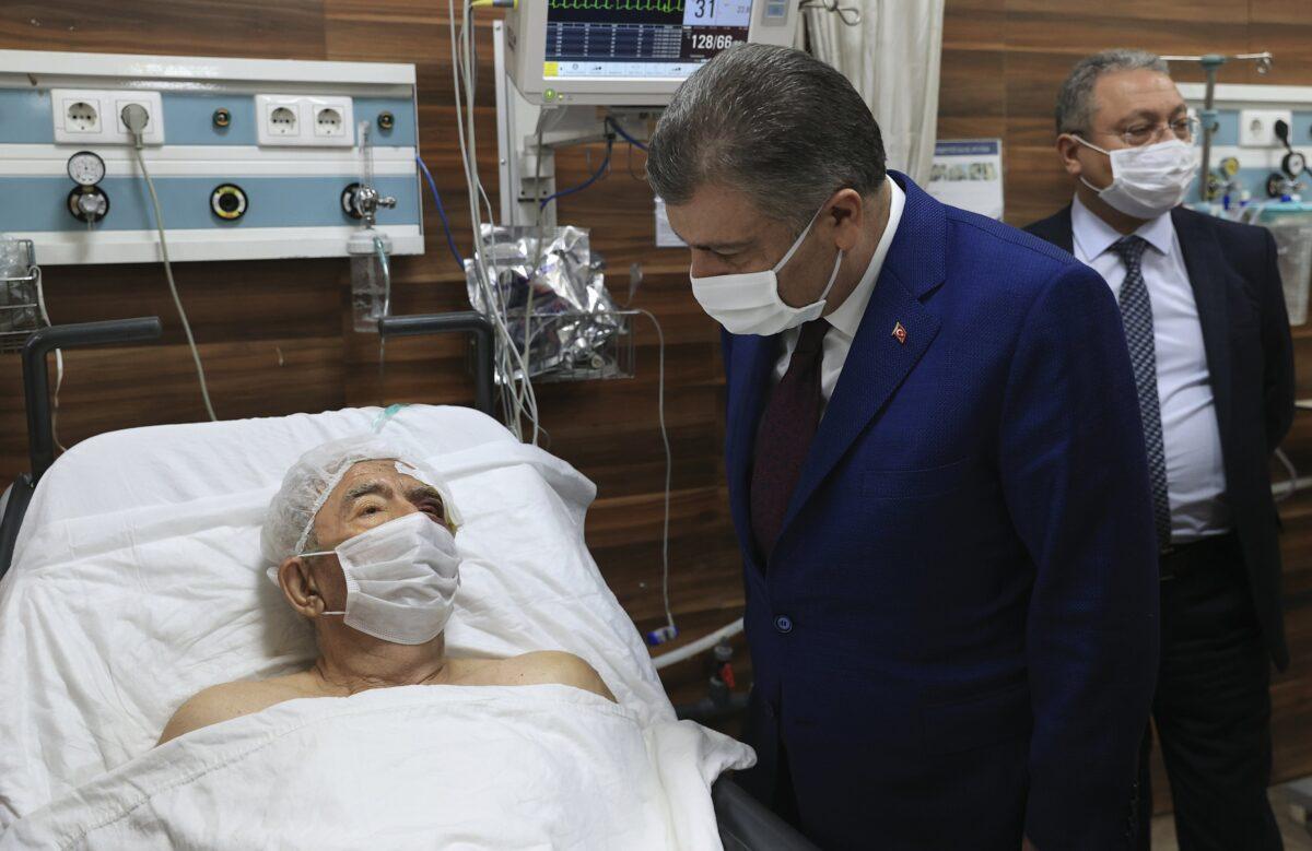 Turkey's Health Minister Fahrettin Koca speaks with Ahmet Citim, rescued from the debris of his collapsed house, in Izmir, Turkey, on Nov. 1, 2020. (Turkey Health Ministry via AP)