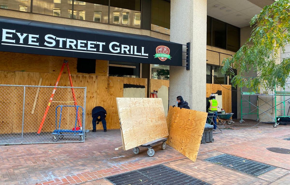 Workers put up plywood to board up buildings as they make plans for potential civil unrest during the U.S. presidential race for the White House in Washington on Nov. 2, 2020. (Daniel Slim/AFP via Getty Images)