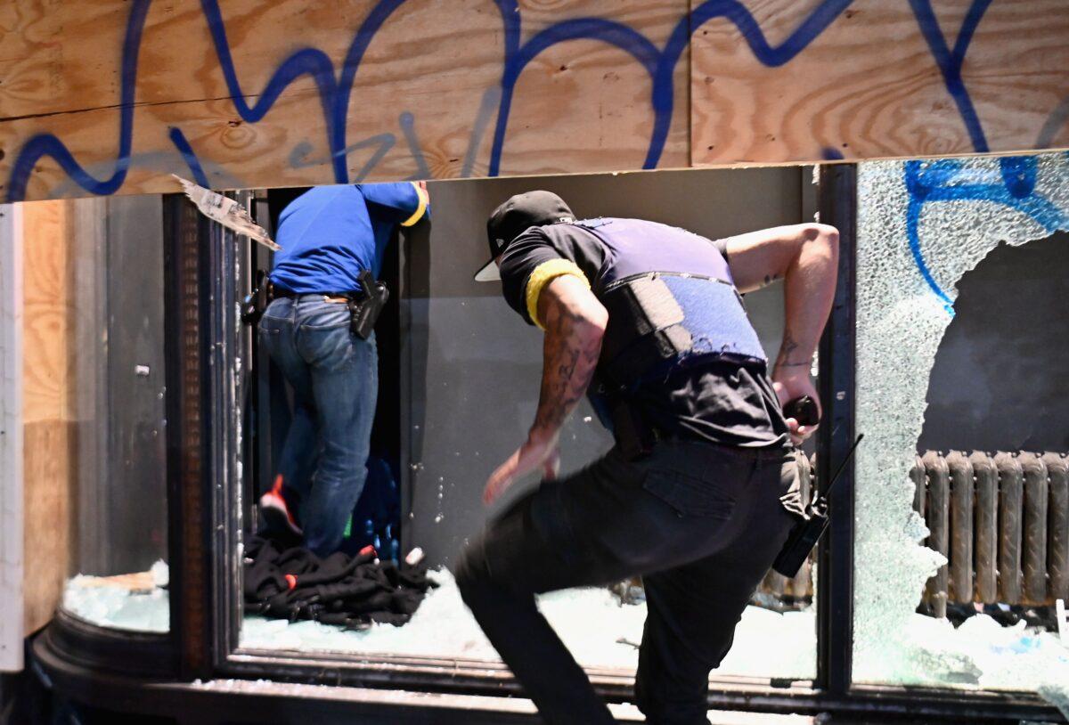 Police officers jump through a broken store window in New York City, on June 2, 2020. (Angela Weiss/AFP via Getty Images)