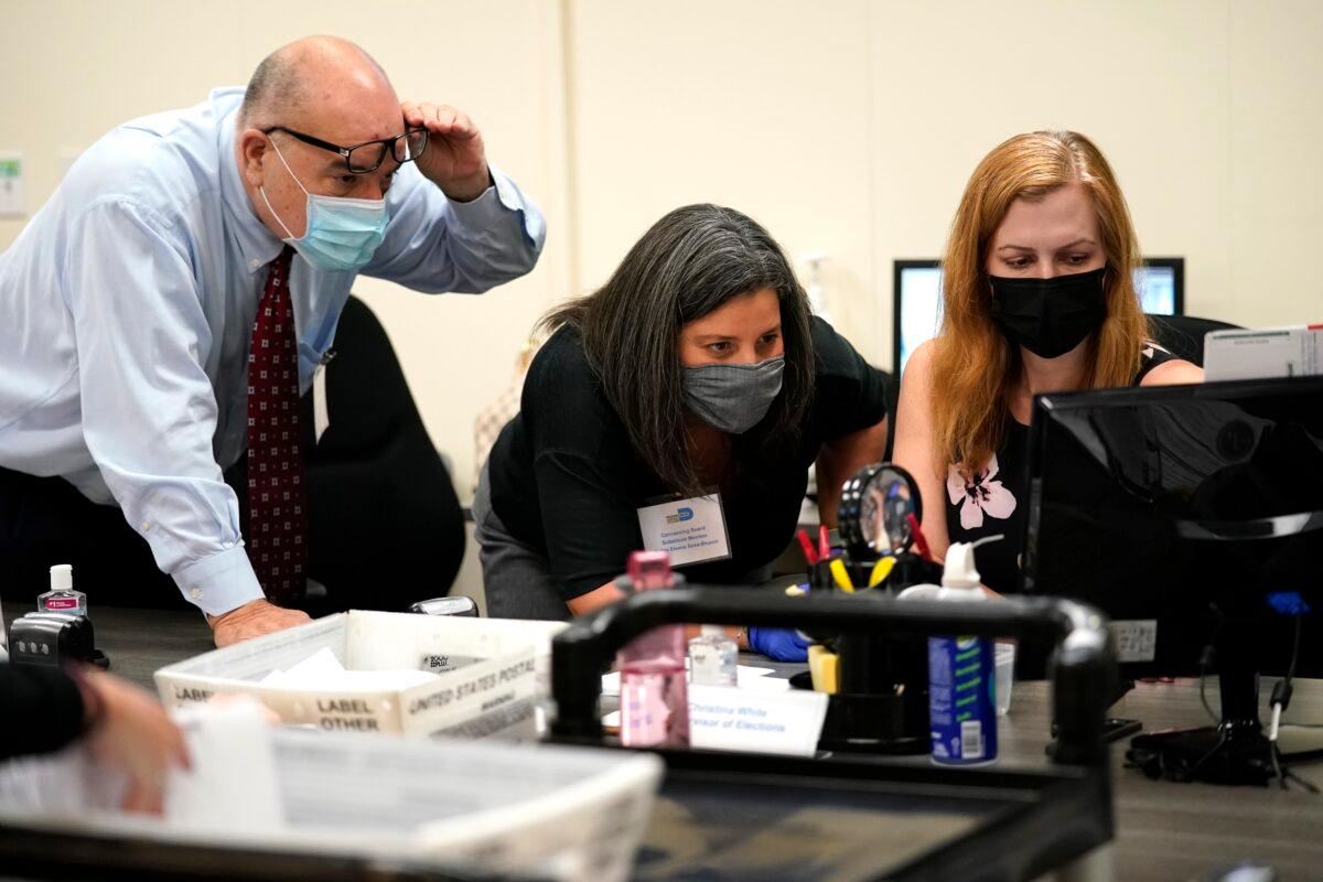 Miami-Dade County Supervisor of Elections Christina White, right, examines signatures on vote-by-mail ballots with members of the Canvassing Board Judge Raul Cuervo, left, and Judge Betsy Alvarez-Zane, center, at the Miami-Dade County Board of Elections in Doral, Fla., on Oct. 26, 2020. (Lynne Sladky/AP Photo)