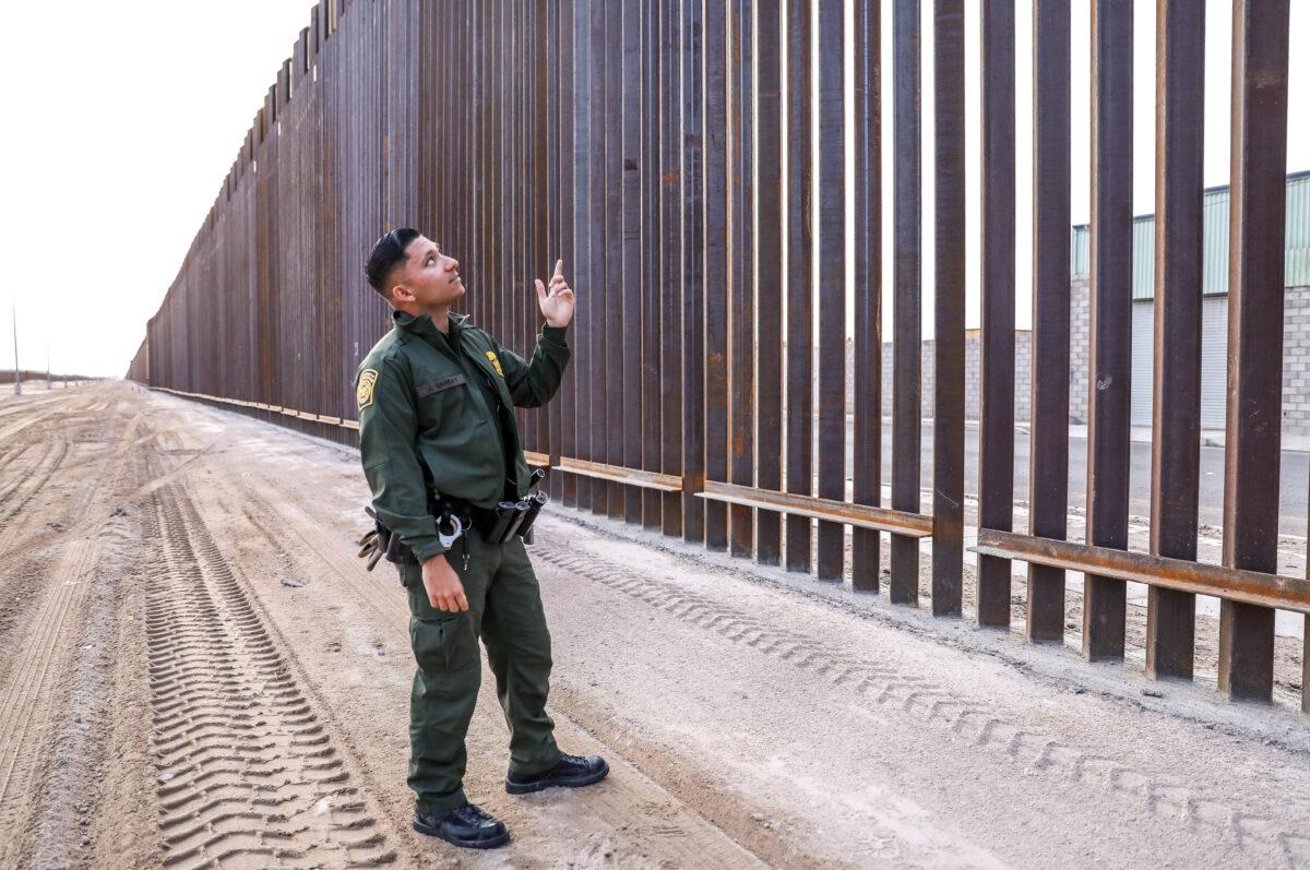 Border Patrol agent Jose Girabay stands next to part of the 30-foot-high, 22-mile new fence on the U.S–Mexico border east of San Luis in Yuma, Ariz., on Nov. 27, 2019. (Charlotte Cuthbertson/The Epoch Times)