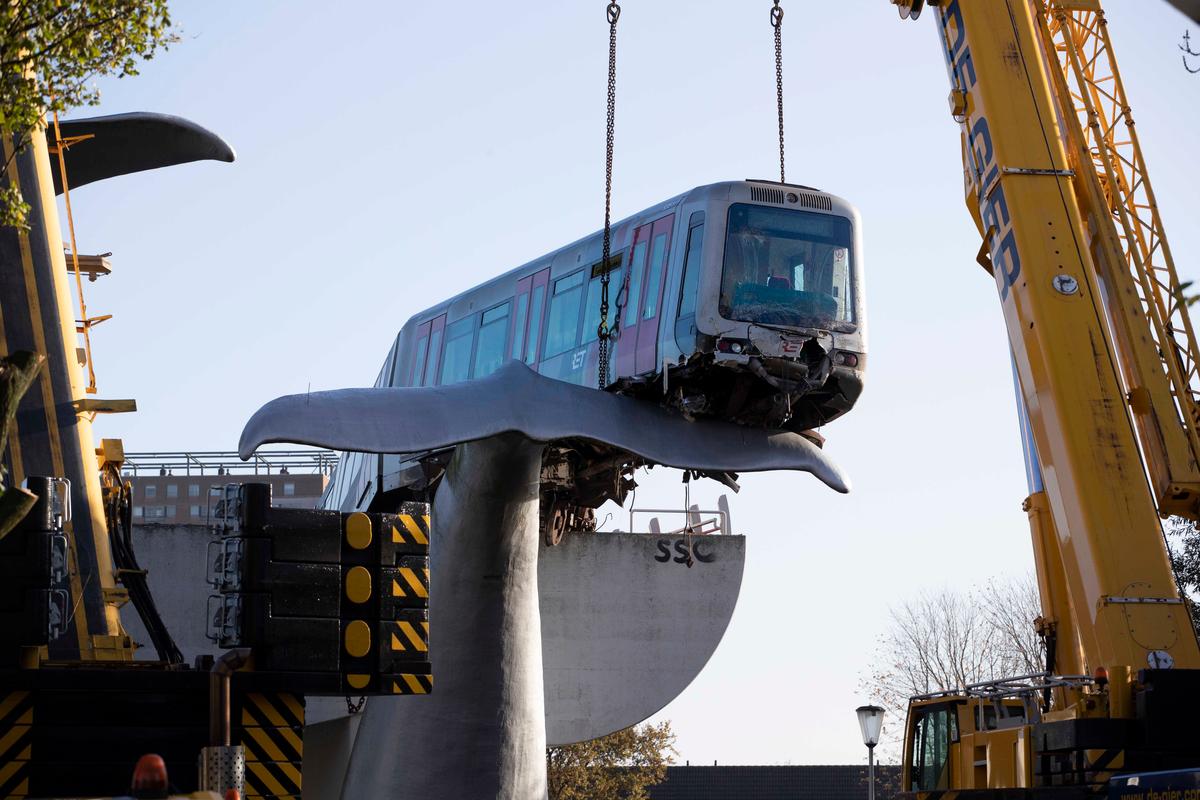 A salvaging crew prepares to attach chains to lift a metro train carriage off the whale's tail of a sculpture after it rammed through the end of an elevated section of rails with the driver escaping injuries in Spijkenisse, near Rotterdam, Netherlands, Tuesday, Nov. 3. (Peter Dejong/AP Photo)