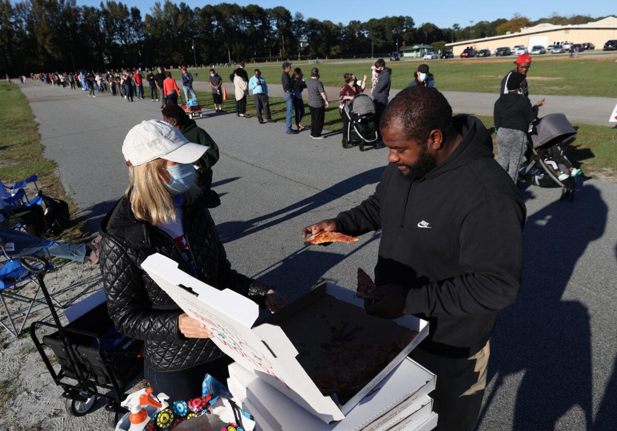 Katie LaFleur (L) passes out pizza to people waiting in line to vote at the Gwinnett County Fairgrounds in Lawrenceville, Ga., on Nov. 3, 2020. (Justin Sullivan/Getty Images)