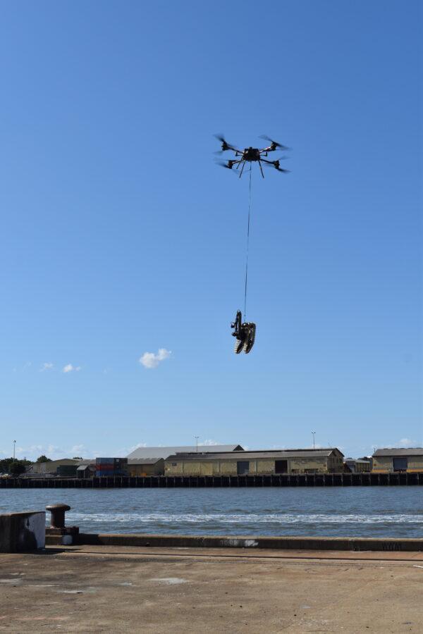 Heavy-lift Drone flying the Light Unmanned Ground Vehicle (UGV) Squad-Packable Utility Robot (SPUR L3025) into location during Exercise GENESIS as part of Autonomous Warrior 2020-4. (ADF)