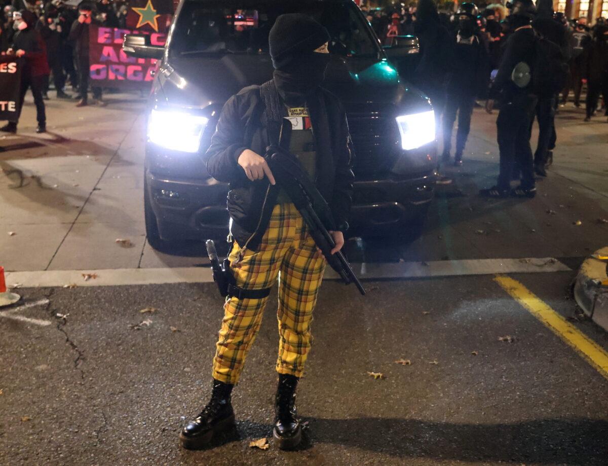 A female demonstrator carries weapons during a protest the day after Election Day, in Portland, Ore., on Nov. 4, 2020. (Goran Tomasevic/Reuters)