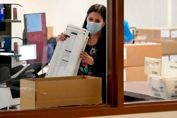 Maricopa County elections officials tally ballots behind boxes of counted forms at the Maricopa County Recorders Office in Phoenix, Ariz., Nov. 4, 2020. (Matt York/AP Photo)