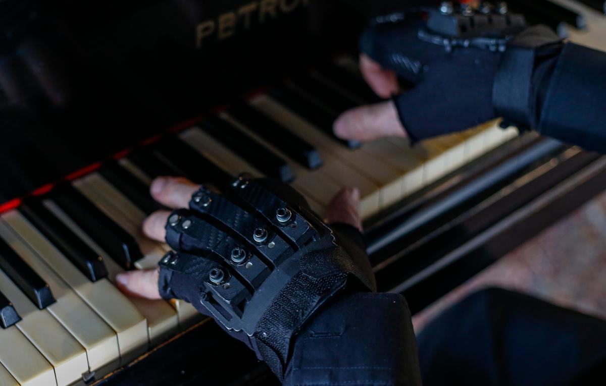 Martins plays the piano while wearing mechanical gloves at his home in Sao Paulo, Brazil, on Jan. 29, 2020. (MIGUEL SCHINCARIOL/AFP via Getty Images)