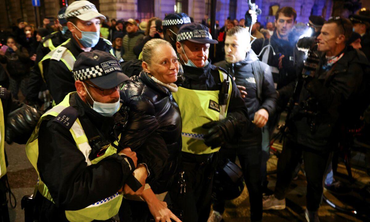  A woman is detained by police officers as protestors from the Million Mask March and anti lockdown protesters demonstrate, amid the CCP virus outbreak in London, on Nov. 5, 2020. (Henry Nicholls/Reuters)