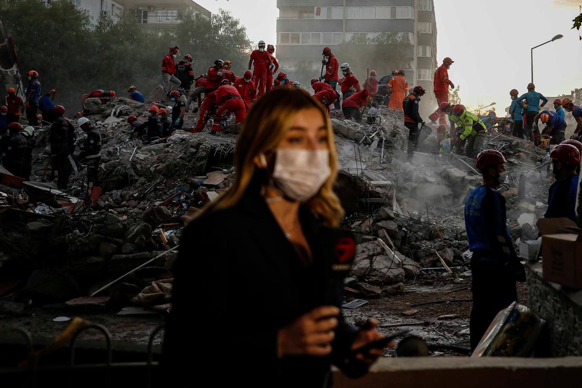 A TV journalist broadcasts from the scene as members of rescue services search for survivors in the debris of a collapsed building in Izmir, Turkey, Monday, Nov. 2, 2020. (Emrah Gurel/AP Photo)