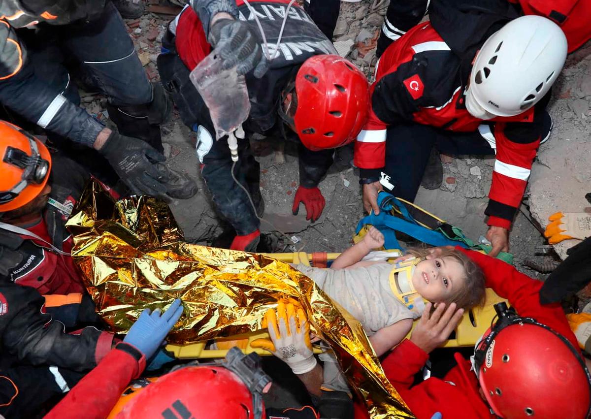 In this photo provided by the government's search-and-rescue agency AFAD, rescue workers, who were trying to reach survivors in the rubble of a collapsed building, surround Ayda Gezgin in the Turkish coastal city of Izmir, Turkey, Tuesday, Nov. 3, 2020. (AFAD via AP)