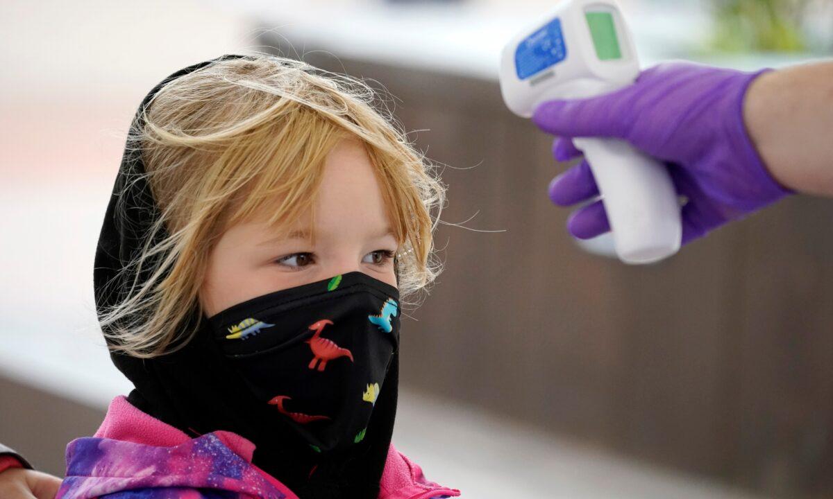 A child wears a mask as she has her temperature checked at the entrance to Alton Towers in Alton, England, on July 4, 2020. (Christopher Furlong/Getty Images)