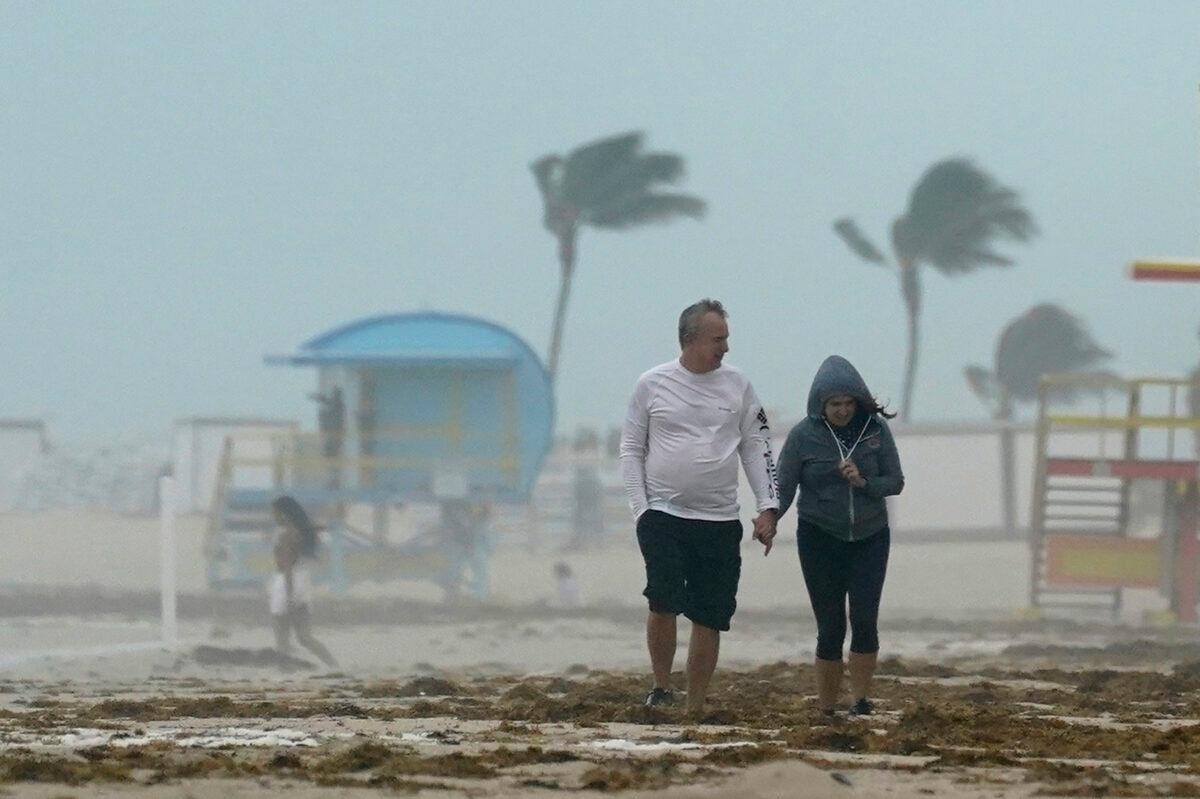 A couple walks along the beach during a downpour, on Miami Beach, Florida's famed South Beach, Fla., on Nov. 8, 2020. (Wilfredo Lee/AP Photo)