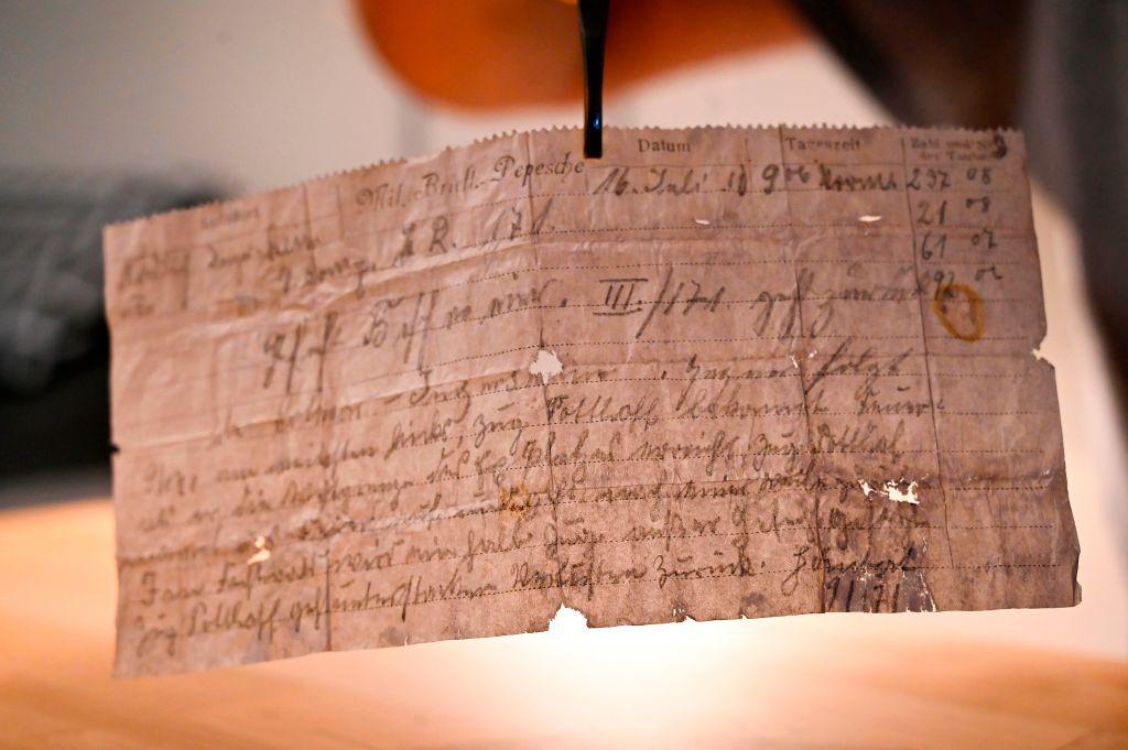 A man shows on Nov. 8, 2020, in Munster, eastern France, a message probably lost by a carrier pigeon in 1910, sent by a German officer and miraculously resurfaced in 2020 in Alsace, where it was found by chance. (SEBASTIEN BOZON/AFP via Getty Images)