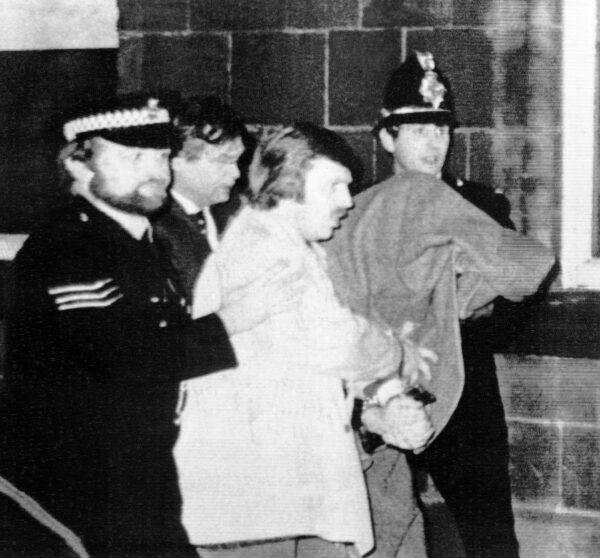 Peter William Sutcliffe, 35, under a blanket at right, being led by police officers from Dewsbury Magistrates Court in Dewsbury, on Jan. 5, 1981. (Pyne, file/AP Photo)