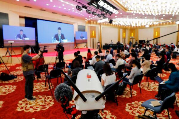 Journalists attend a news conference by Guo Weimin (back L-on screen), spokesman for the National Committee of the Chinese People's Political Consultative Conference (CPPCC), as he speaks via video link at the media center in Beijing, China on May 20, 2020. (Thomas Peter/AFP via Getty Images)