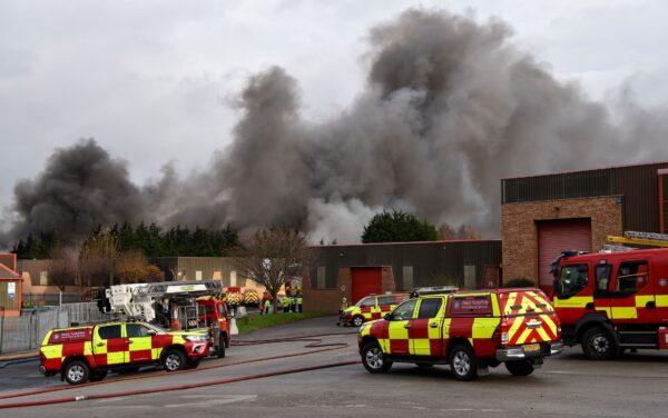 Fire fighters are seen with thick smoke from a blaze involving a large quantity of tyres at a location near the railway's Bradford Interchange in Bradford, Northern England, on Nov. 16, 2020. (West Yorkshire Fire & Rescue Service)
