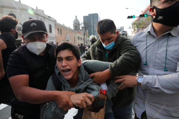 Plainclothes policemen detain a supporter of ousted President Martin Vizcarra near a police barricade, preventing marchers who are refusing to recognize the new government from reaching Congress, in Lima, Peru, on Nov. 11, 2020. (AP Photo/Rodrigo Abd)