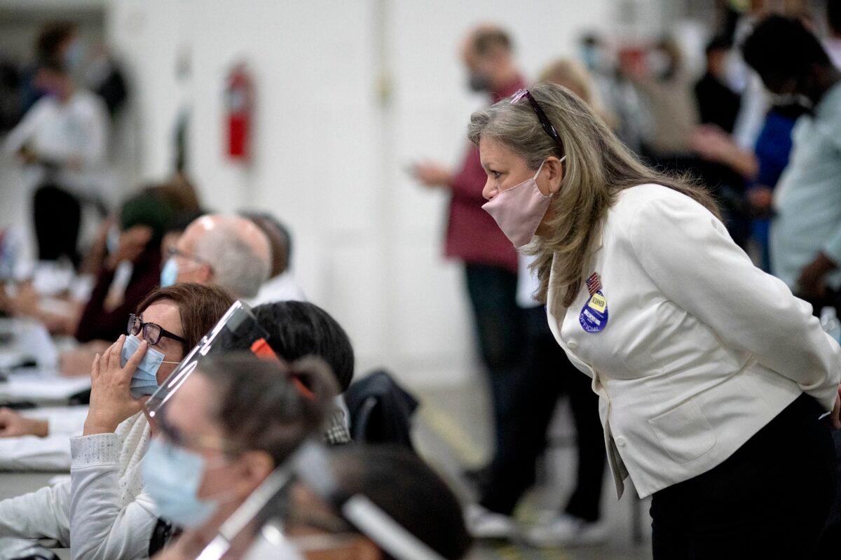 A Republican election challenger at right watches over election inspectors as they examine a ballot as votes are counted into the early morning hours at the central counting board in Detroit, Mich., on Nov. 4, 2020. (David Goldman/AP Photo)