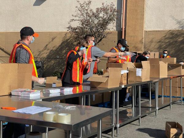 Volunteers with masks stuff boxes for Thanksgiving at the Second Harvest Food Bank in Irvine, Calif., on Nov. 19, 2020. (Drew Van Voorhis/The Epoch Times)