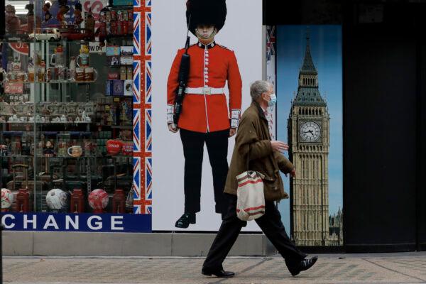 A person wearing a face mask walks past a temporarily closed souvenir store on Oxford Street, during England's second  CCP virus lockdown in London, on Nov. 23, 2020. (AP Photo/Matt Dunham)