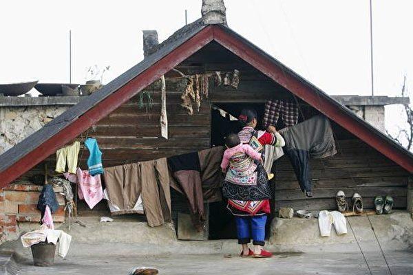 A woman of the Yi ethnic group airs clothes from the roof of her home in Yuanyang County, Yunnan Province, on Feb. 11, 2006. (Photo by Cancan Chu/Getty Images)