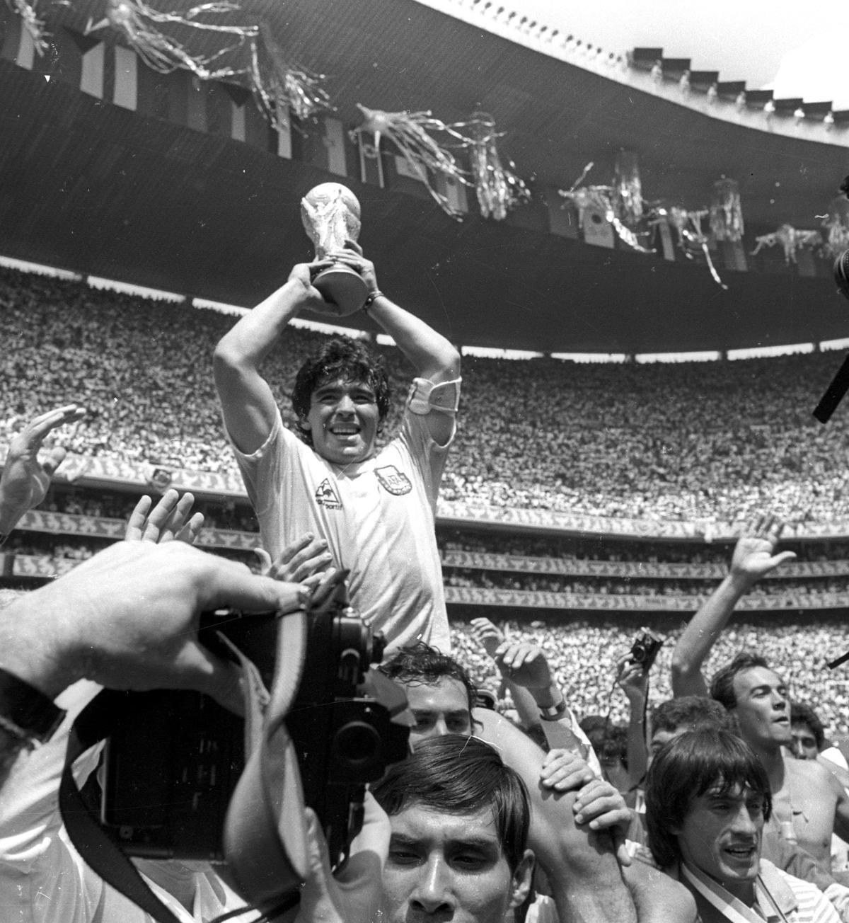 Argentine star Diego Maradona holds up the World Cup trophy as he is carried off the field after Argentina defeated West Germany 3–2 to win the World Cup soccer championship in Mexico City on June 29, 1986. (Gary Hershorn/Reuters)