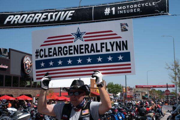 Dane Senser carries a sign in support of General Michael Flynn as motorcyclists ride on Main Street during the 80th Annual Sturgis Motorcycle Rally in Sturgis, S. Dak. on Aug. 8, 2020. (Bryan R. Smith/AFP via Getty Images)