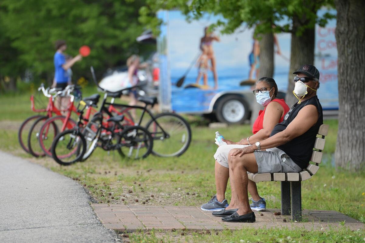 A man and woman sit with their masks on at Creve Coeur Lake Park in Maryland Heights, Mo., on May 25, 2020. (Michael Thomas/Getty Images)