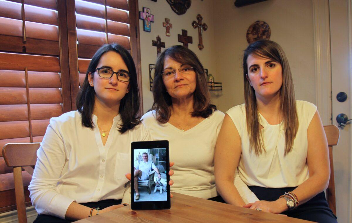 Dennysse Vadell sits between her daughters Veronica (R) and Cristina holding a digital photograph of father and husband Tomeu who is currently jailed in Venezuela, in Katy, Texas., on Feb. 15, 2019. (John L Mone/File/AP Photo)