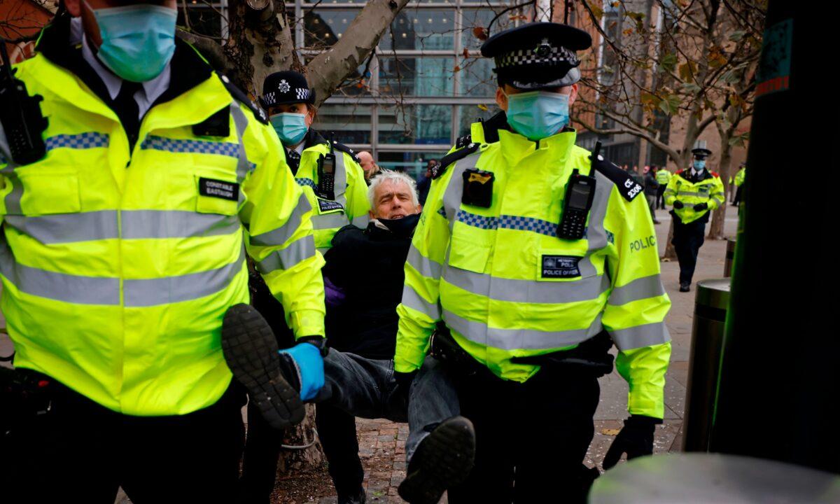 Police officers take away a man ahead of an anti-lockdown protest against government restrictions designed to control or mitigate the spread of the CCP virus, including the wearing of masks and lockdowns, at Kings Cross station in London. on Nov. 28, 2020. (Tolga Akmen/AFP via Getty Images)